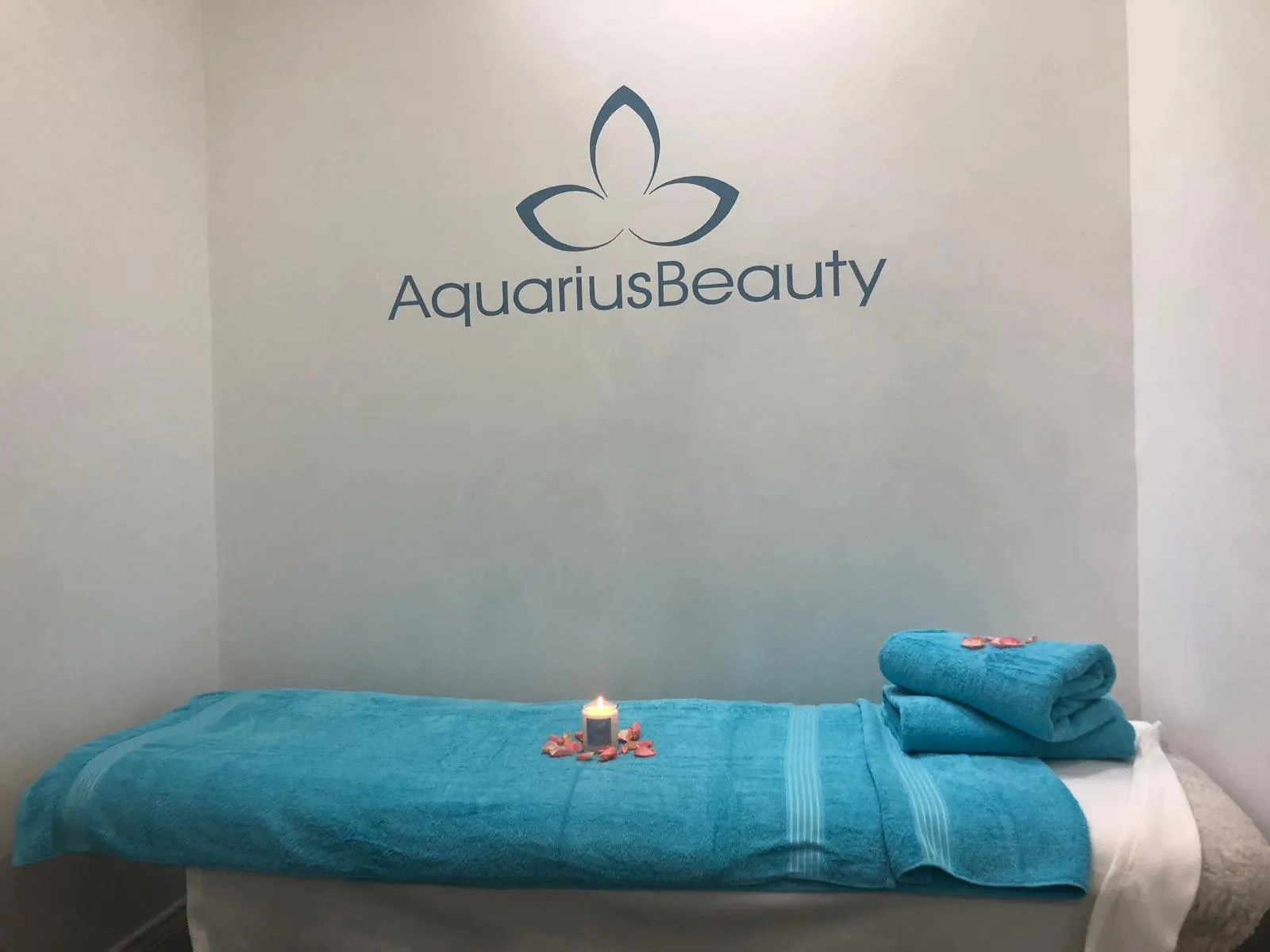 Treatment room at Aquarius Beauty, with the salon logo above a towel-covered treatment bed